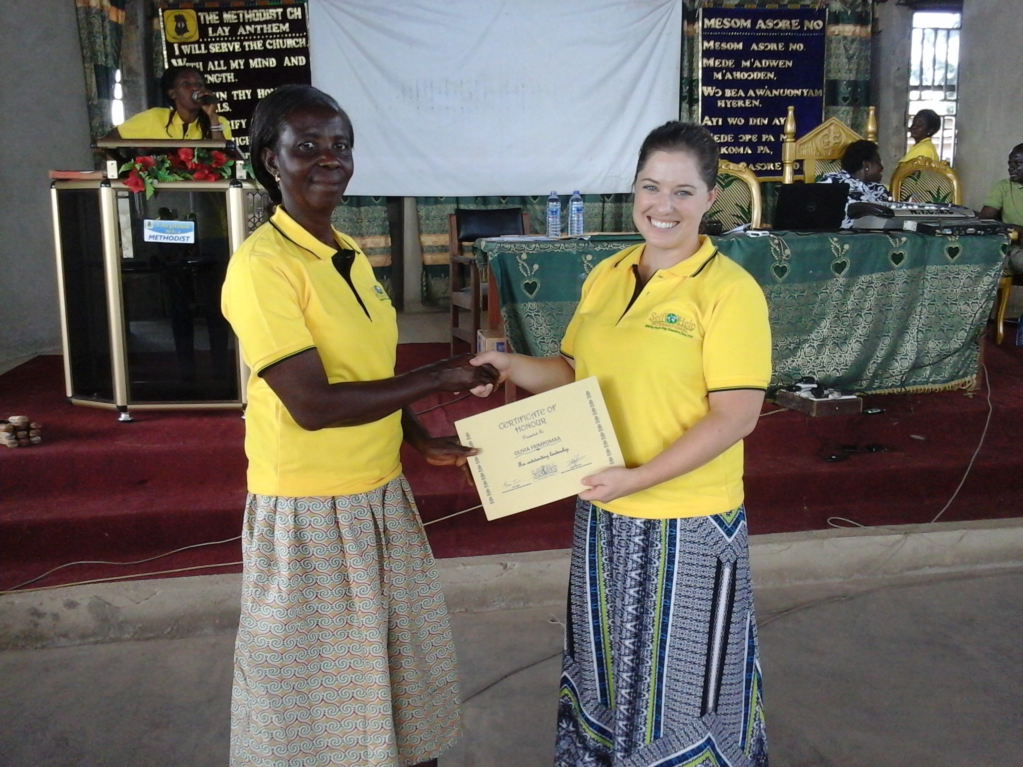 a young woman, Olivia is awarded a certificate for her hard work form SHI's executive director, Nora Tobin