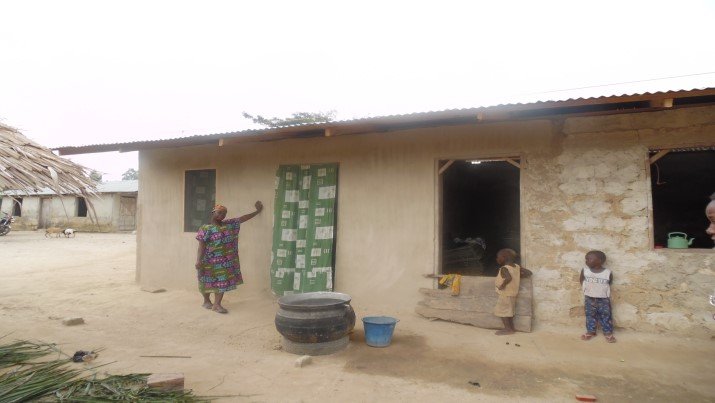 Ayishetu in front of her partly completed house