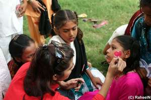 A volunteer paints a heart on a student's cheek