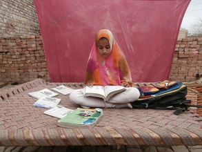 Qaisra reading from her coursework at home