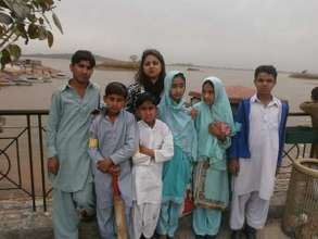 students, cricket bat in hand, pose by the lake