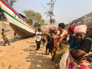 Local women help pull the boat to the water