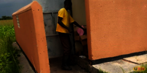 Ogaali entering into the office in the pit latrine