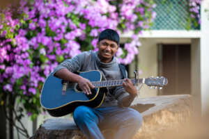 Sitting out on the big stump, Rampal plays guitar.