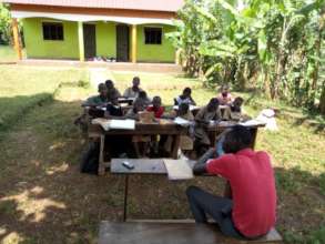 Children taking a class under a tree shade