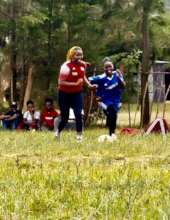 a teacher and a girl student playing soccer