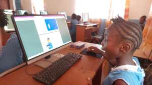 FAWE Student Reading a Book in the Computer Lab