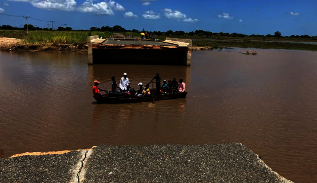 (People crossing a flooded road by boat)
