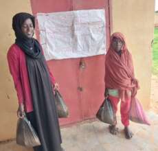 Goat beneficiary with a sack of seed in Lawabid