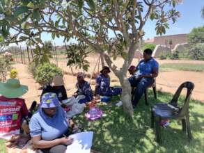 Tsogang Bosele members meet under a tree in 2023
