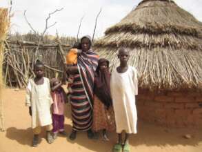 Fatima with her family outside their hut