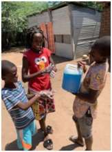 Children using sanitation gel made by the women.