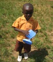 Kofi, a pupil, carrying his bowl.