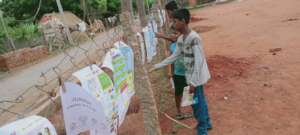 Reading children's newsparers on the village fence