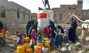 Women & children gather as water tanks are filled.