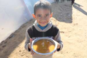 A boy holding a large bowl of tasty lentils