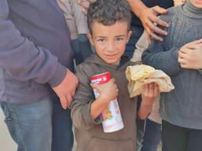 A child holding bread and canned meat
