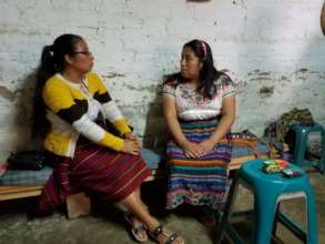 Adelina (left) chats with a savings group member