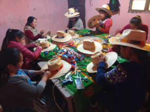 Our "fijadoras" attach the woven bands to the hats