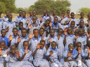 Ayak Anguei girls waving, wearing new uniforms