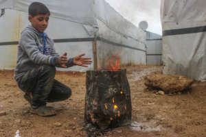 A refugee kid warming his hand