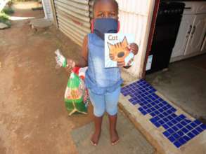 Supporting this child with a mask, book and bread