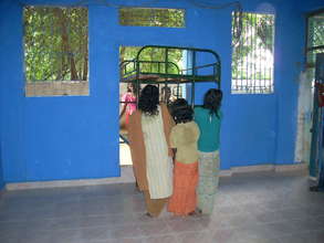 Children bring cots in to the new room