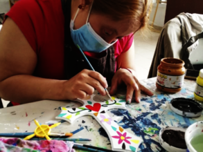 Andrea painting a wooden cross
