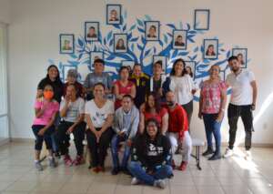 Happy community members in front of the blue tree
