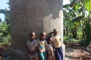 children leaning on a water tank