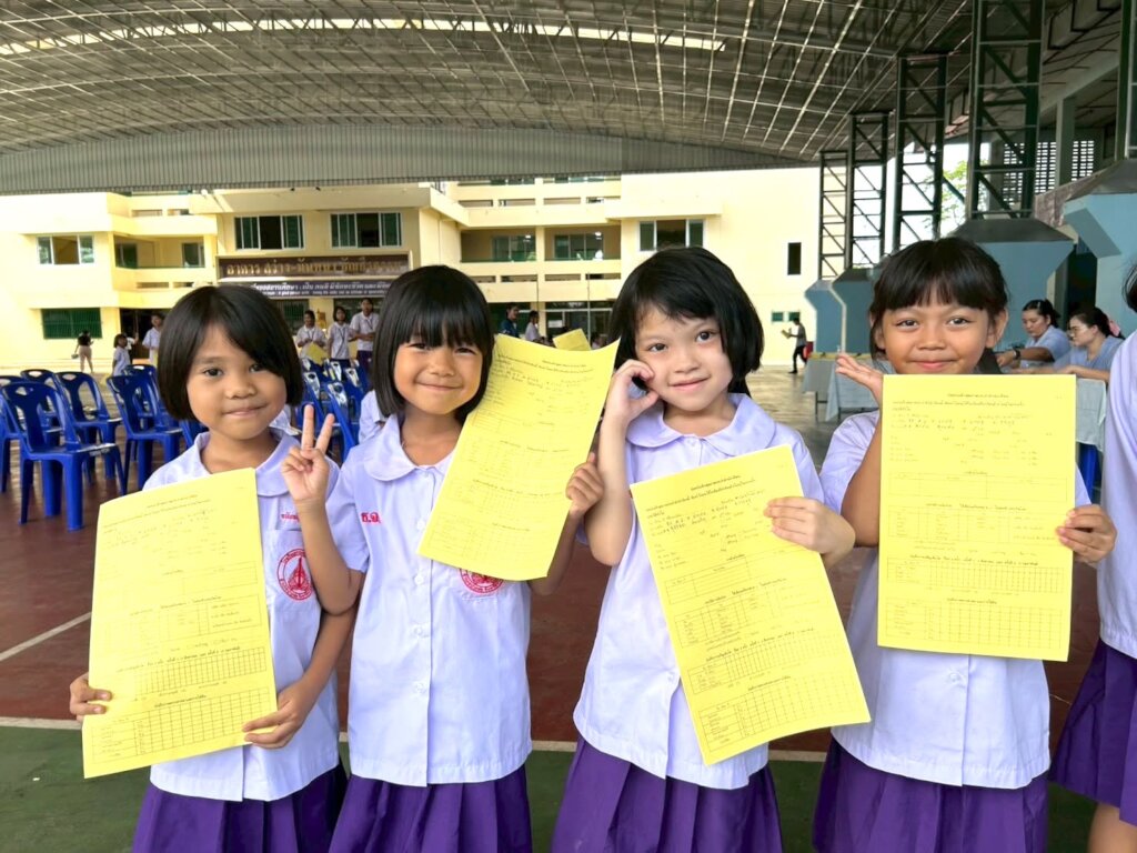 Girls proudly hold their Health Screening charts