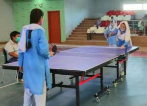 A competitive table tennis match between students.