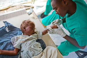 A doctor takes care of a young cholera patient.