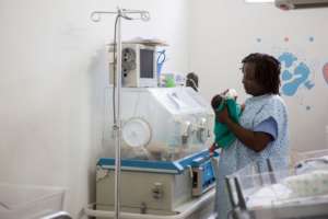 Thamar Julmiste feeding a newborn in the NICU