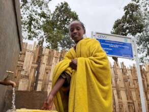 rural girl fetching water from a well built by DOW