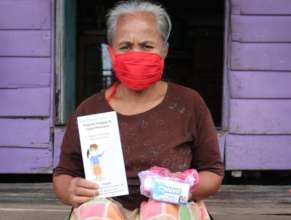 An elderly receiving masks, soaps and a flyer