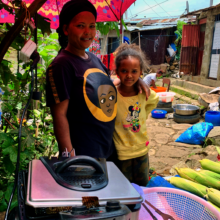 Daughter stands with mom, a microloan recipient.