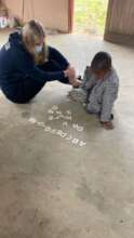 A volunteer teaching alphabets to a NCP child