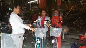 Sreynan (right) in orange suit with her bike