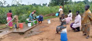 Joice, sitting on white bucket, waits her turn.