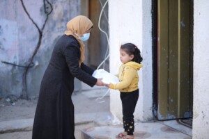 A team member handing a young girl a fresh meal.
