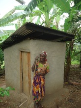 Christine standing with her new pit latrine