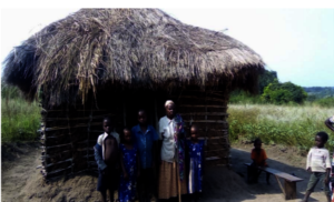 Phausta & Family In Front Of Grass Thatched Home