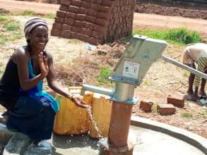 Woman enjoying refurbished well at Makukuba Mende