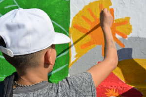 Adolescent in street situation painting a mural