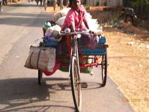 Girl child riding tri-cycle load of waste paper