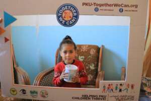 A PKU child holding can of medical formula