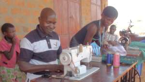 John Guiding Students in the Art of Sewing