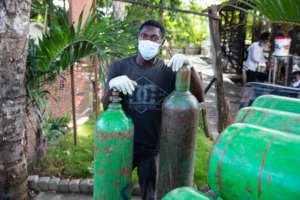A staff member with bottles of medical oxygen.