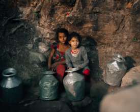 Children waiting to collect water form a creek
